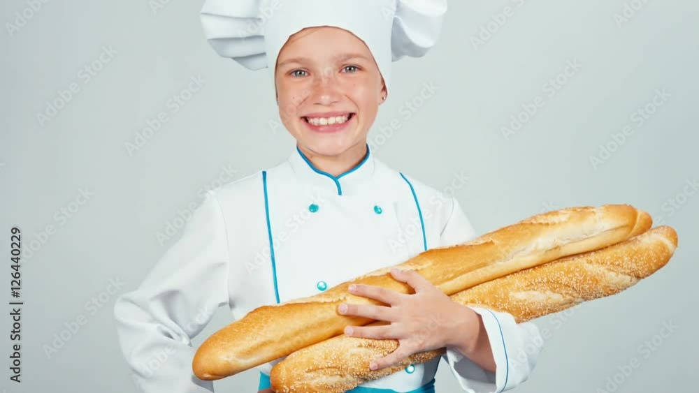 Baker girl 7-8 years child holds bread baguettes and smiling at camera. Zooming Baker girl 7-8 years child holds bread baguettes and smiling at camera. Zooming