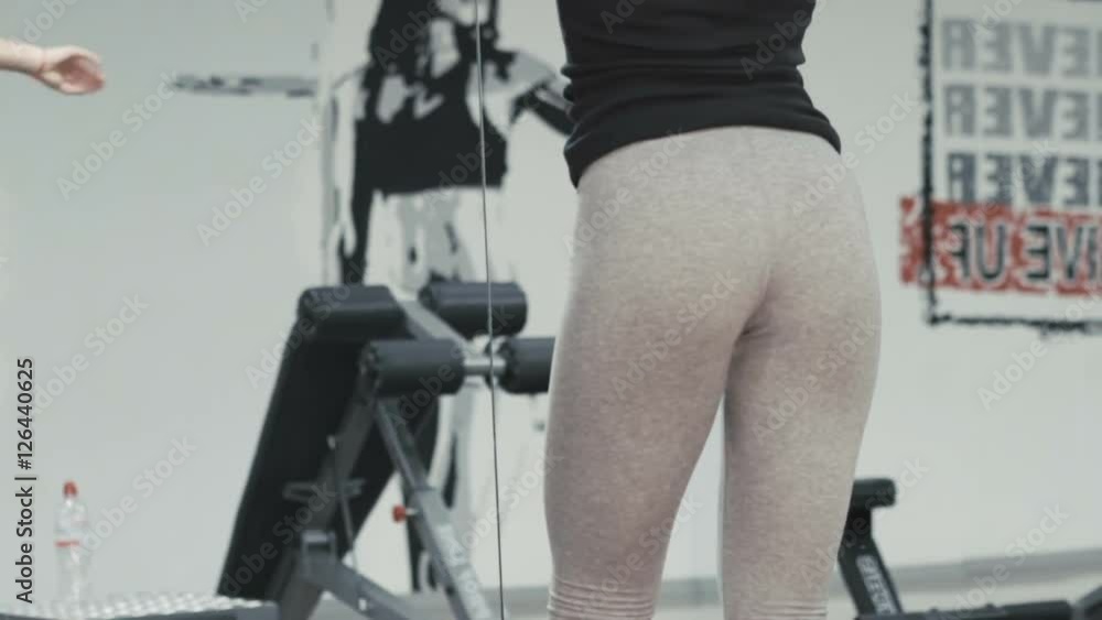 Slim girl stretching her legs' muscles with exercise in the modern gym Slim girl stretching her legs' muscles with exercise in the modern gym