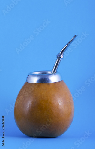 yerba mate in gourd matero with bombilla on blue background