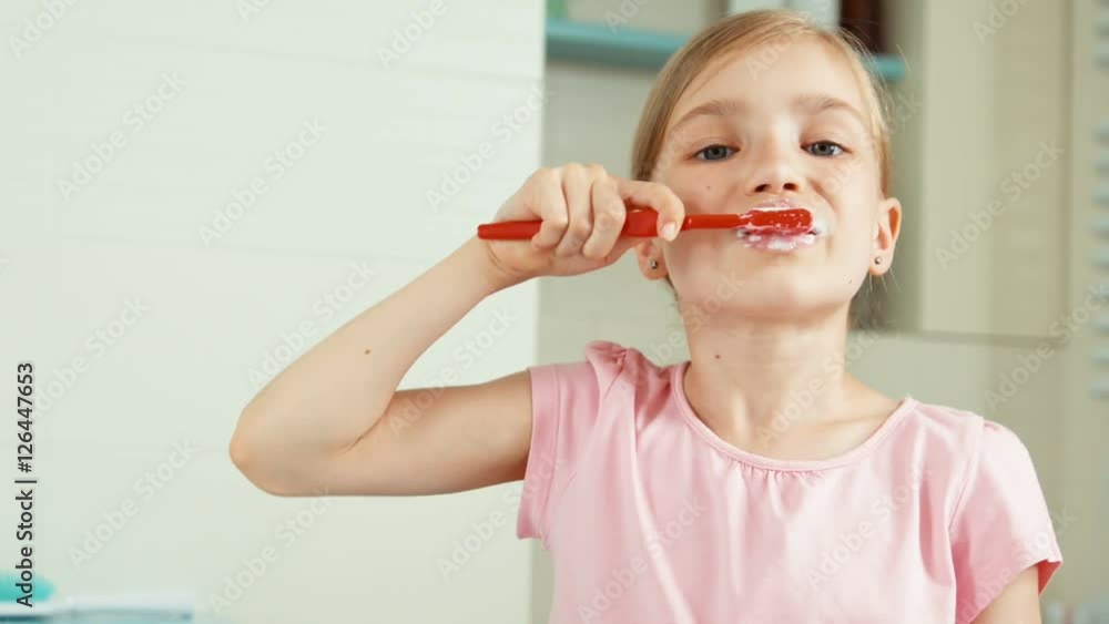 Close up portrait girl 7-8 years old using toothpaste and smiling at camera. Child puts toothpaste on the brush and cleaning teeth Close up portrait girl 7-8 years old using toothpaste and smiling at camera. Child puts toothpaste on the brush and cleaning teeth