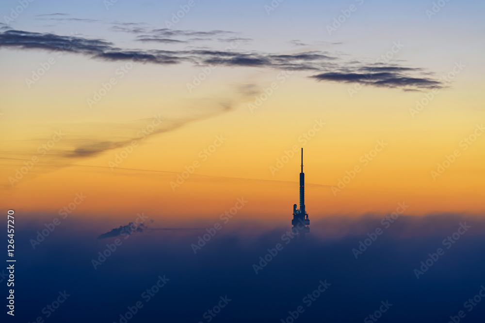 Fototapeta premium Wieża telewizyjna Zizkov o wschodzie słońca z dużą chmurą mgły i niesamowitym niebem. Praga. Republika Czeska.