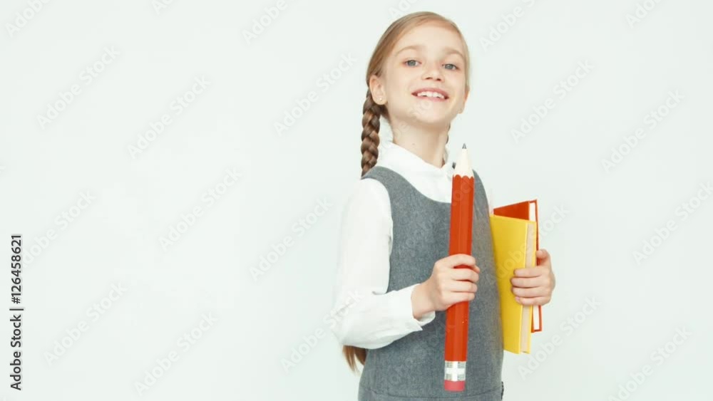 Cute happy schoolgirl child 7-8 years on white background turns around at camera and smiling. Girl holding books Cute happy schoolgirl child 7-8 years on white background turns around at camera and smiling. Girl holding books