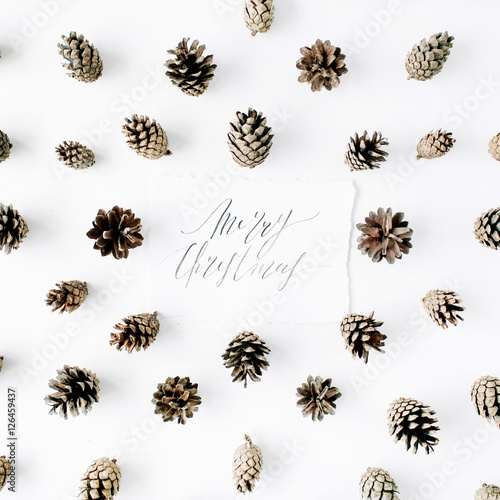 words merry christmas and minimal creative cone arrangement pattern on white. flat lay, top view. christmas background wallpaper.