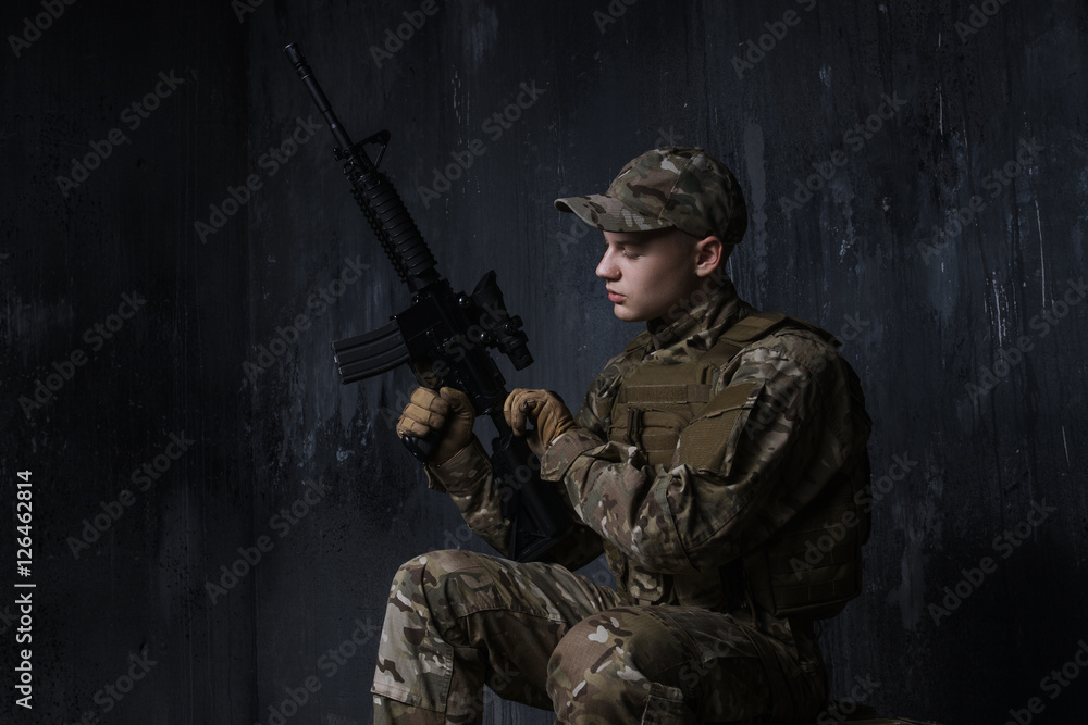 Young soldier sitting and recharges automatic in the dash. Practice shooting. Young soldier sitting and recharges automatic in the dash. Practice shooting.