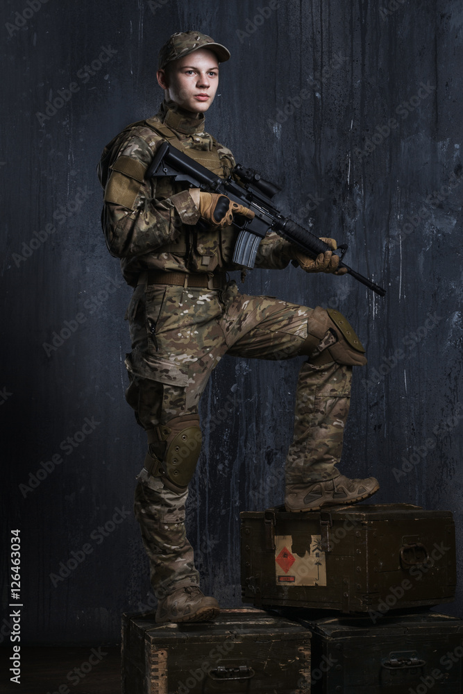 Fototapeta premium Young men standing on boxes with a rifle. Confident and proud look