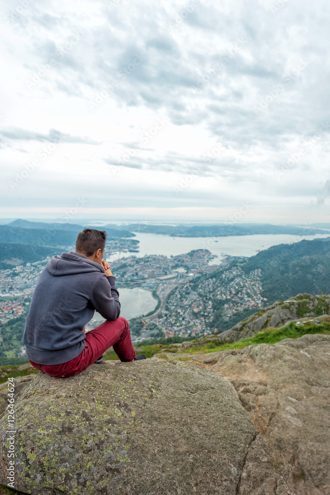 Man is sitting on cliff's and looking to valley Man is sitting on cliff's and looking to valley