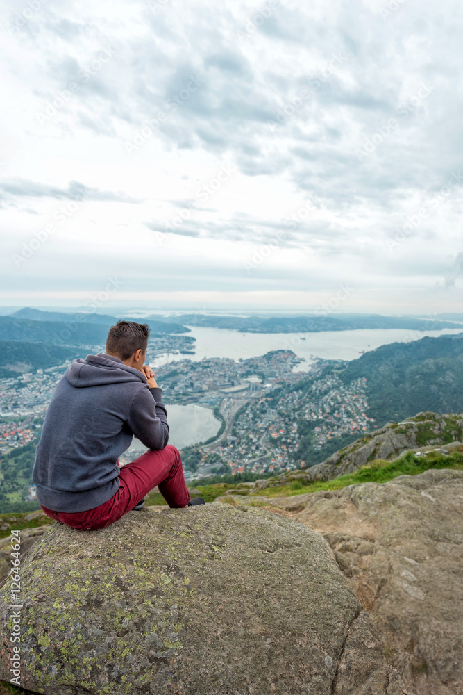 Man is sitting on cliff's and looking to valley