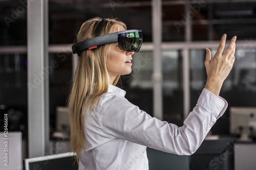Virtual reality device. Woman playing game in virtual reality glasses. Headset  with virtual screen. Girl touch something using modern glasses with virtual screen. 