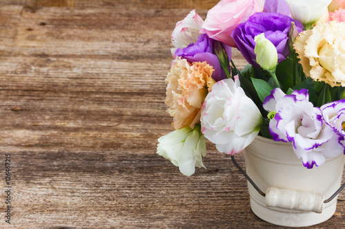 Pink  white and violet eustoma flowers in pot on aged wooden background