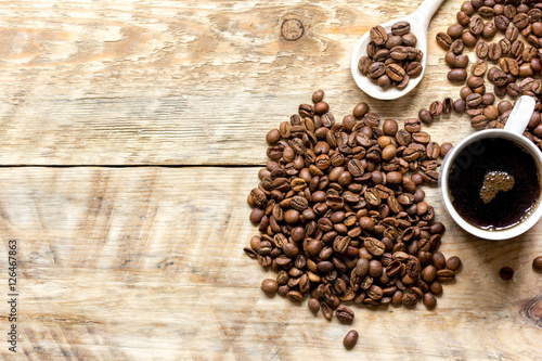 cup of coffee, beans and spoon on wooden background