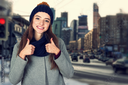 Portrait of a cheerful woman showing thumbs up standing  over  background  of big city megapolis © kristiana1992