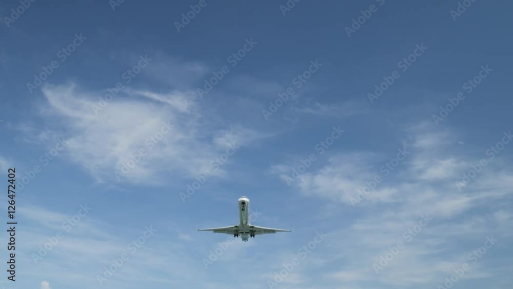 Airplane landing on island Bali airport under blue sea with waves on the horizon. Cinematic shot of overhead flying aircraft with beautiful ocean on cloudy sky background. Focal length 50 mm Airplane landing on island Bali airport under blue sea with waves on the horizon. Cinematic shot of overhead flying aircraft with beautiful ocean on cloudy sky background. Focal length 50 mm
