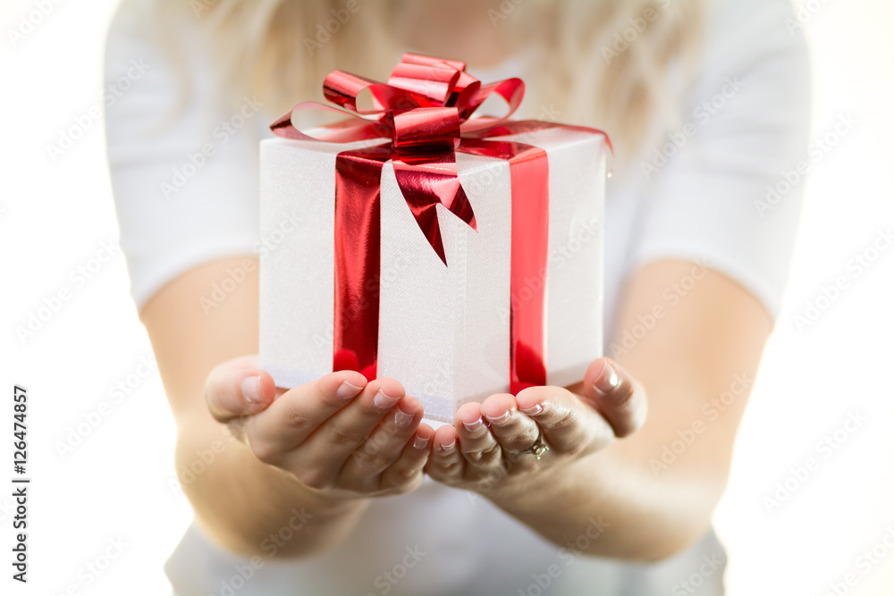 blonde girl woman holds white Christmas gift present with shiny red ribbon nice hands white background