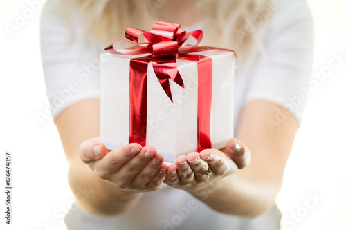 Obraz na płótnie blonde girl woman holds white Christmas gift present with shiny red ribbon nice hands white background w salonie