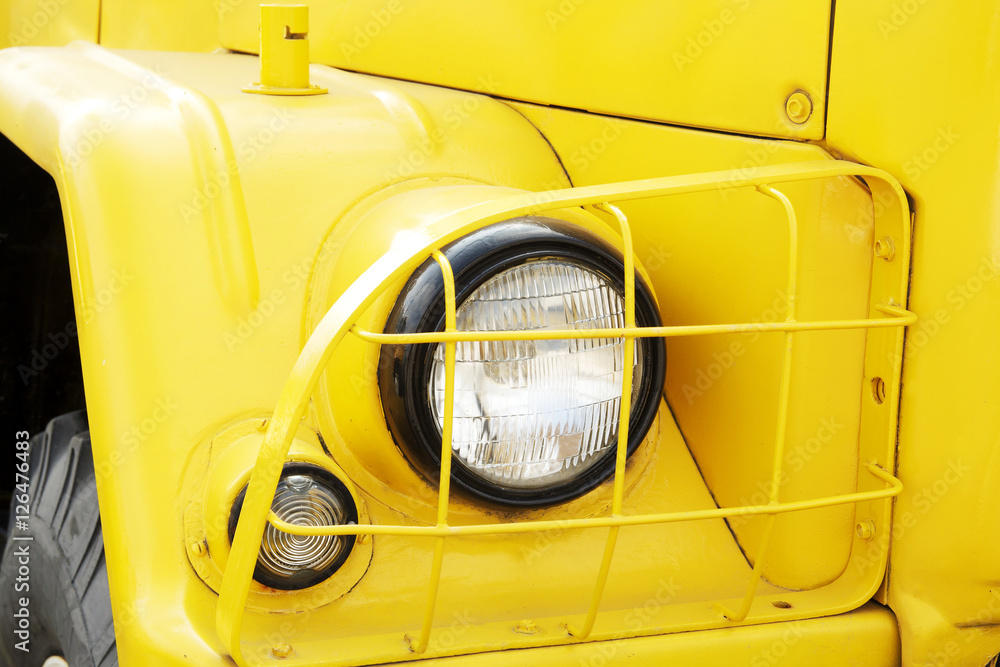 Yellow vintage car on a festival of old cars. Retro car's headlight close up.