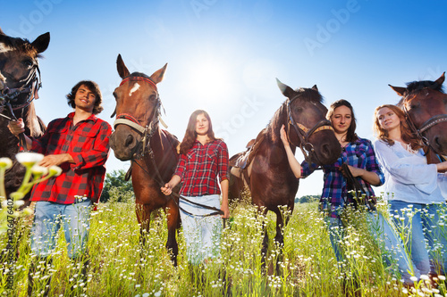 Young people standing in a row with their horses