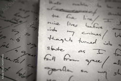 Lyrics written on paper in black ink close up. Focus on the words 