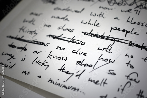 Lyrics written on paper in black ink close up. Focus on the words 