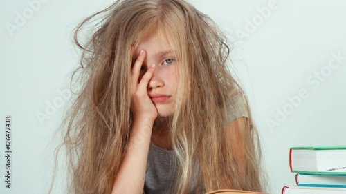 Portrait tired sad girl 7-8 years old does not want to study and reading books. Zooming