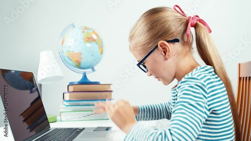 Schoolgirl child 7-8 years using credit card and her laptop and smiling with smile at camera. Thumb up. Ok. Zooming photo