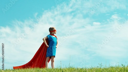 Super hero girl child 7-8 years old protects the world against the blue sky. Zooming