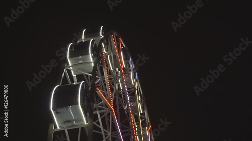 Ferris wheel rotating at amusement park under dark night sky photo