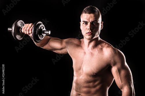 muscular young man lifting weights isolated with black background