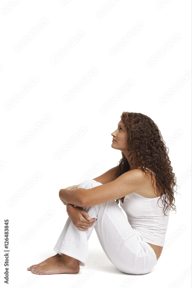 Profile of woman sitting on floor, arms around knees Stock Photo