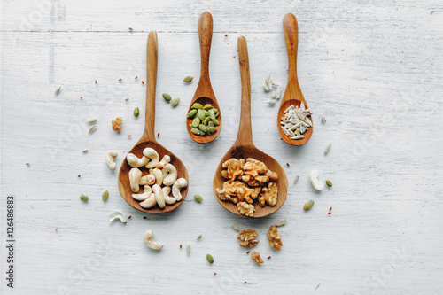 Obraz na płótnie Four wooden spoons with seeds and nuts on thw white table w salonie