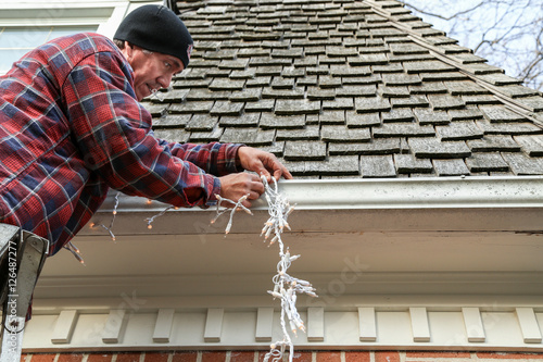 side on of man hanging Christmas lights