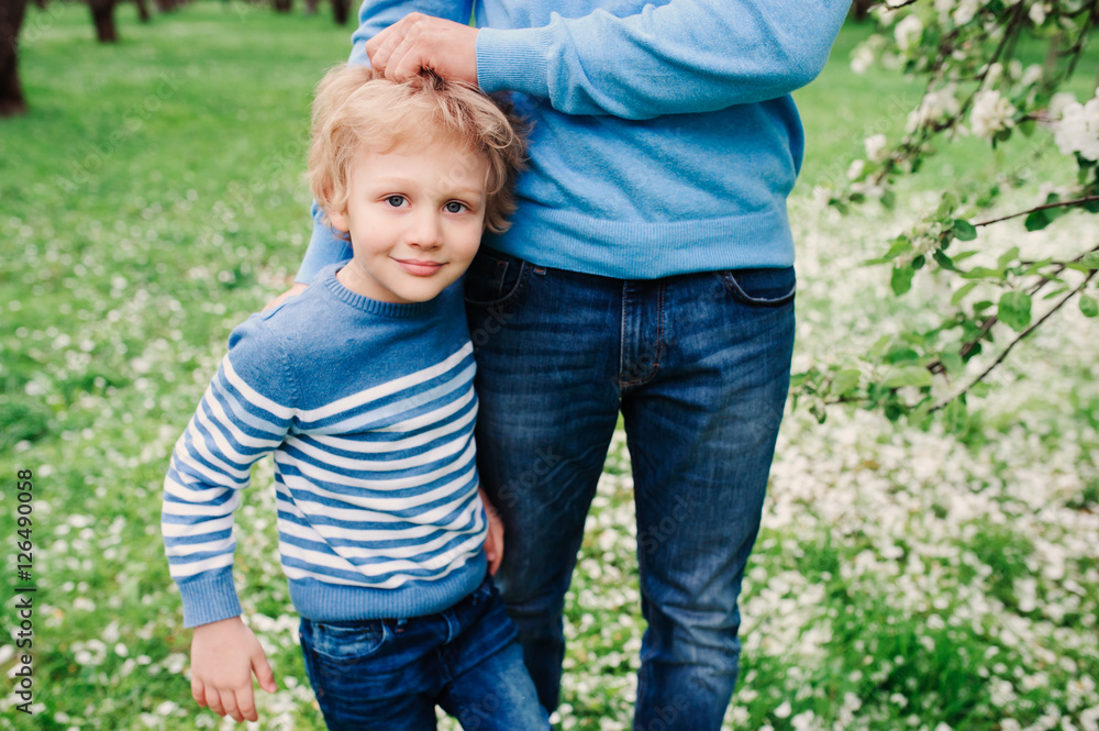 spring portrait of happy child boy enjoying walk with father in blooming apple garden spring portrait of happy child boy enjoying walk with father in blooming apple garden