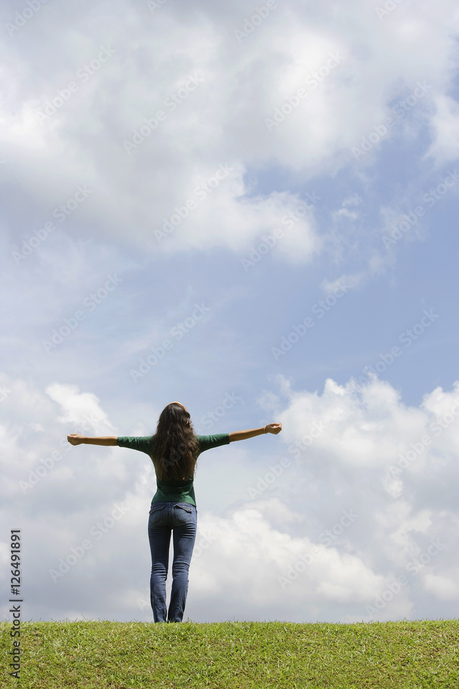 Teen girl standing on grass, arms spread Teen girl standing on grass, arms spread