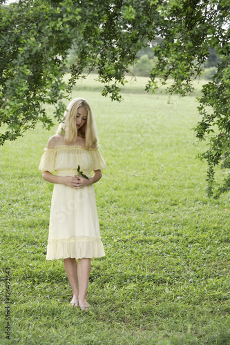 Young woman in yellow dress in green field