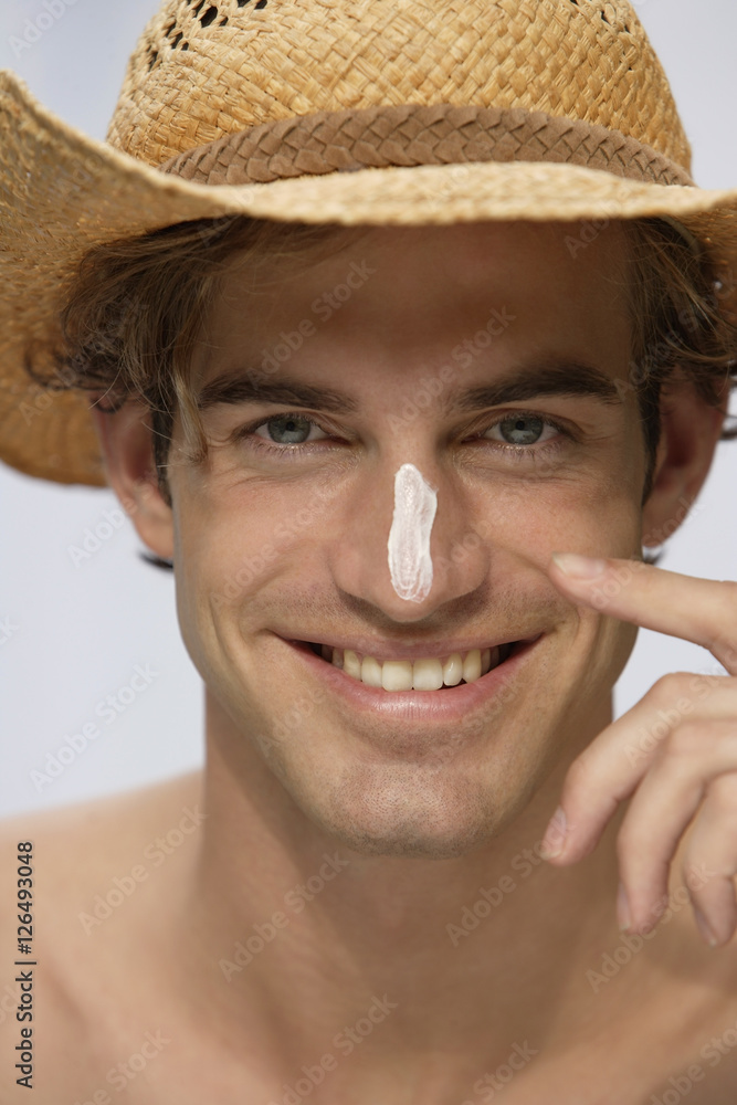 young man wearing hat with sunblock on nose
