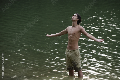 Fototapeta Naklejka Na Ścianę i Meble -  Young man standing in lake, arms open wide