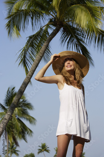 Woman standing under palm trees © Alexander