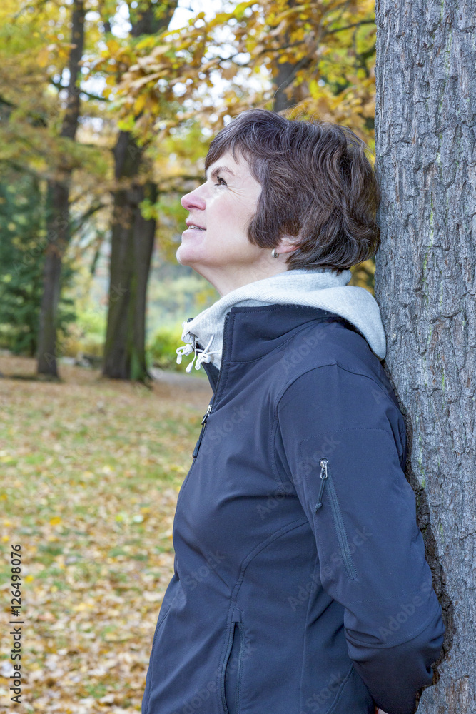 Woman leans in the tree and enjoys the autumn wood Woman leans in the tree and enjoys the autumn wood