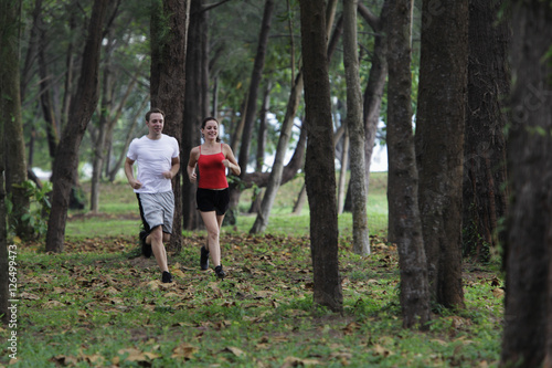 young couple running together through trees