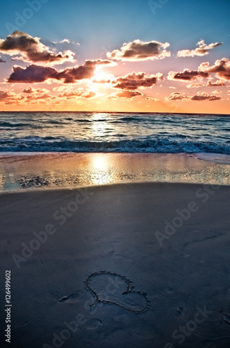 a heart on the beach at sunset