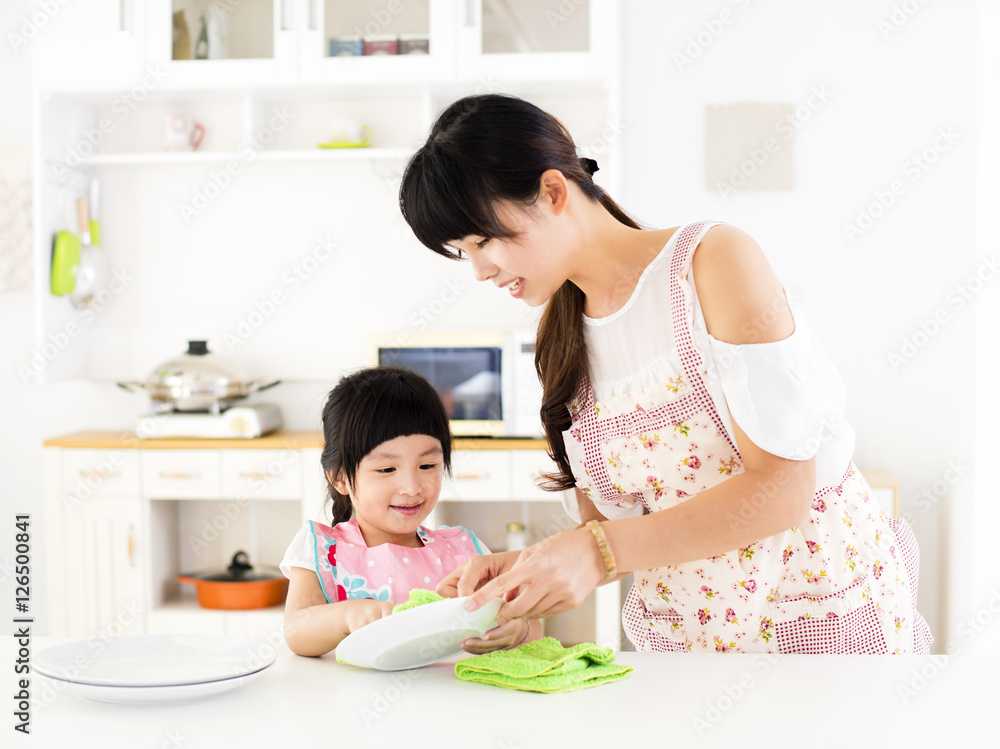 little girl helping her mother clean dish in the kitchen little girl helping her mother clean dish in the kitchen