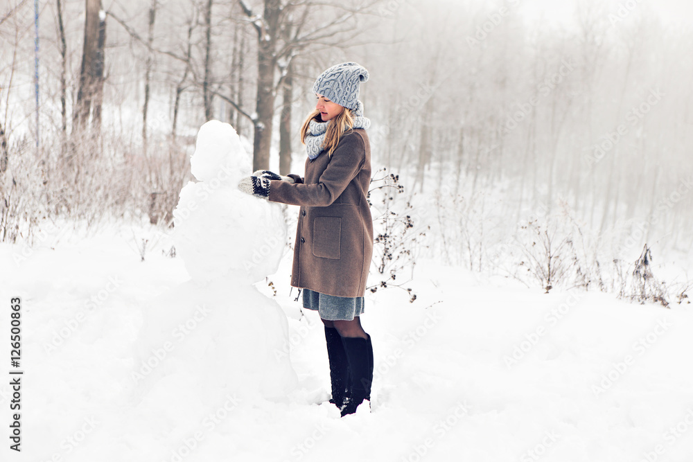 Woman making a snowman in winter time Woman making a snowman in winter time