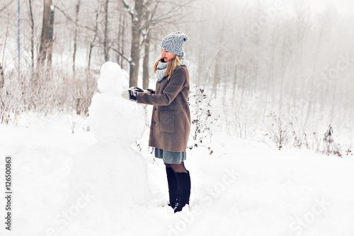 Fotografia Woman making a snowman in winter time