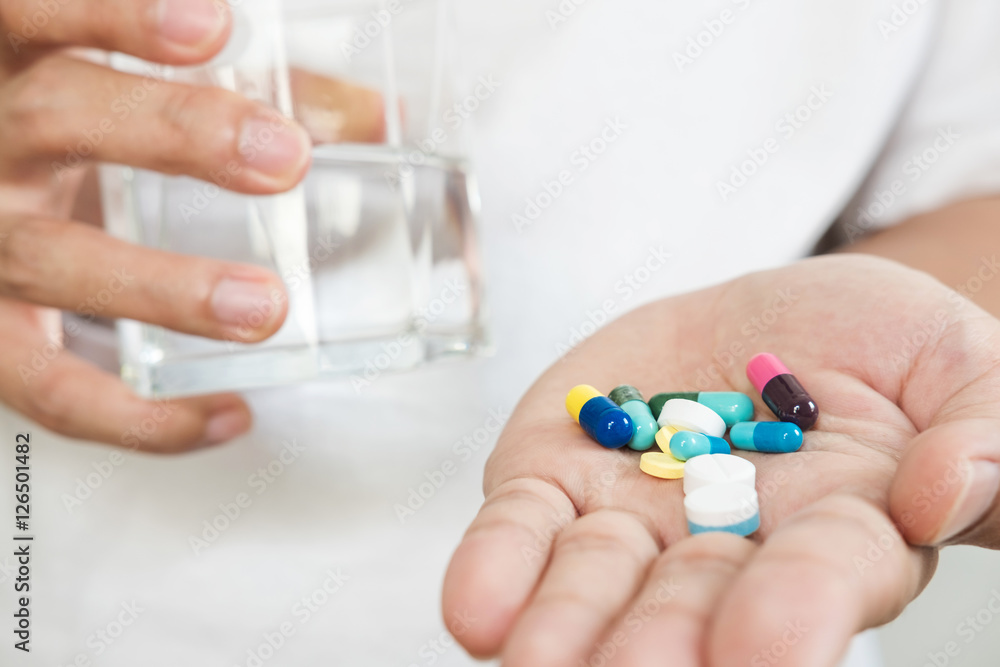 Pills and capsules on hand with glass of water, men body health concept Pills and capsules on hand with glass of water, men body health concept