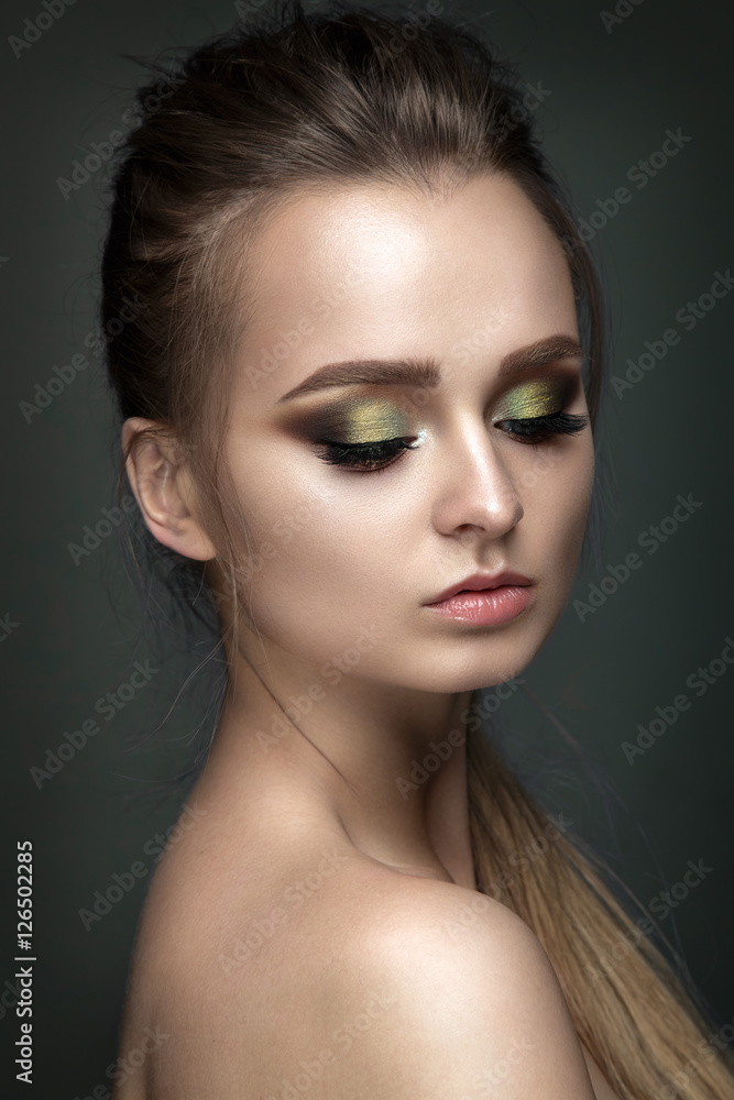 Beautiful woman portrait on grey background with green eye shadows. Beautiful woman portrait on grey background with green eye shadows.