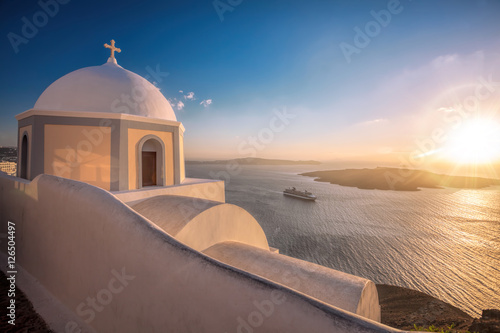 Old Town of Thira on the island Santorini, white church against colorful sunset in Greece