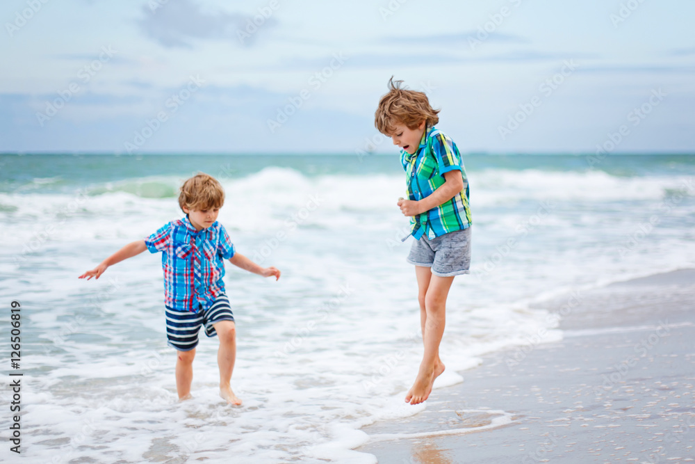 Two little kids boys running on the beach of ocean