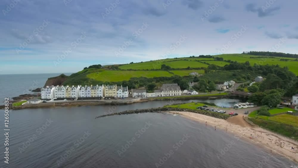 Aerial shot of the houses in the Cushendun Village near the coast of the big sea and the big mountain on the back Aerial shot of the houses in the Cushendun Village near the coast of the big sea and the big mountain on the back
