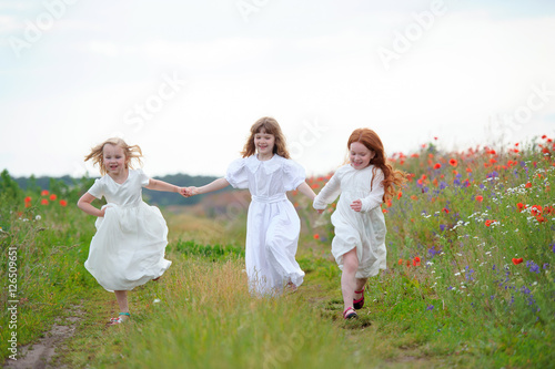 happy children friends sisters run and play outdoors on the mead