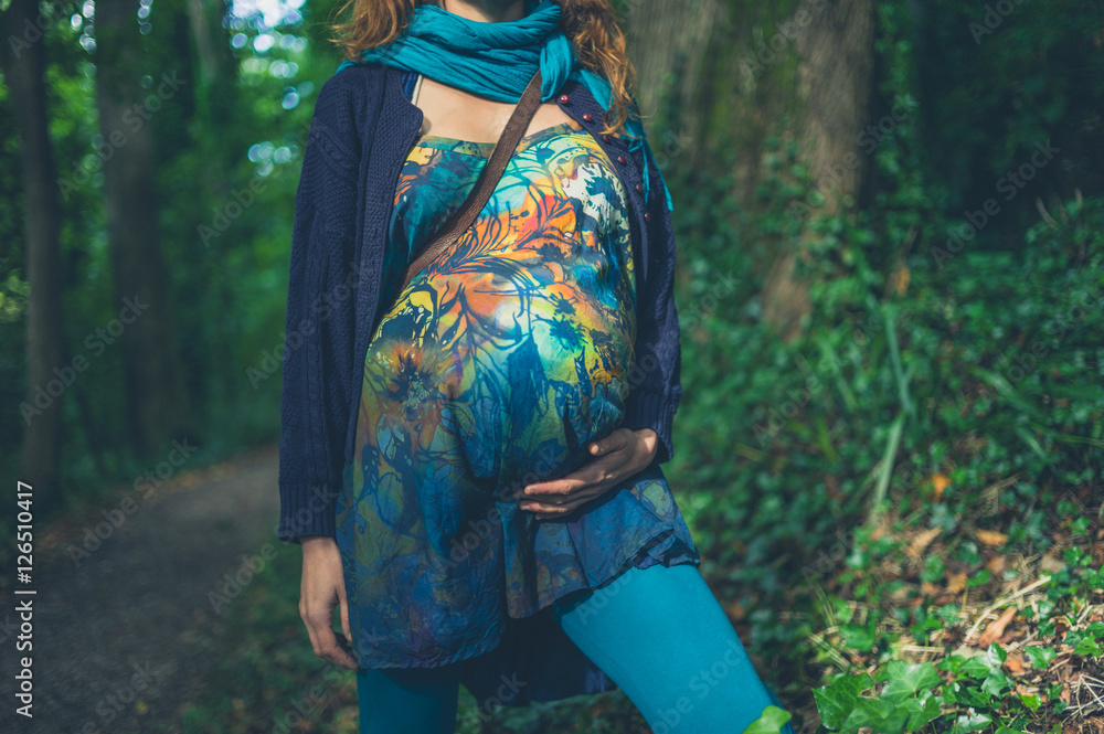 Young pregnant woman standing in the forest