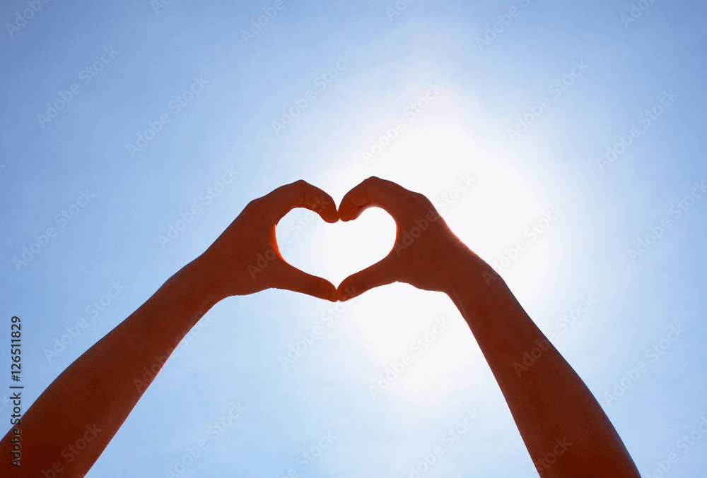 Fototapeta premium Girls made heart of his hands on the sky.